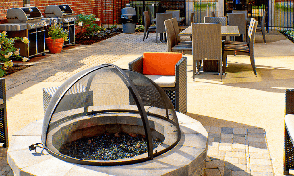 a fire pit on a patio with chairs and tables